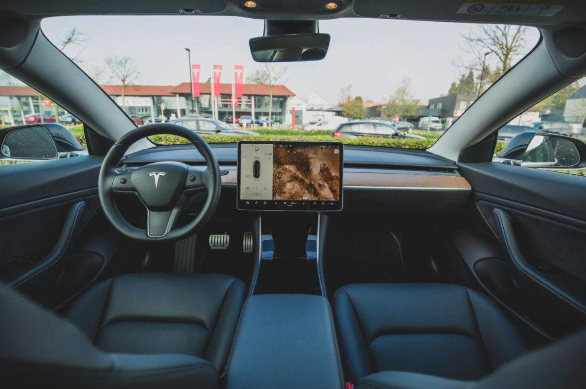Tesla Model 3 interior dashboard display and steering wheel, showcasing autonomous driving technology.