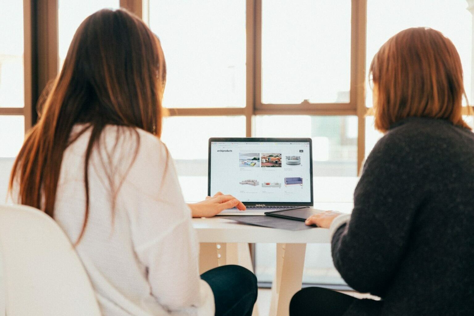 a woman and a girl looking at a laptop