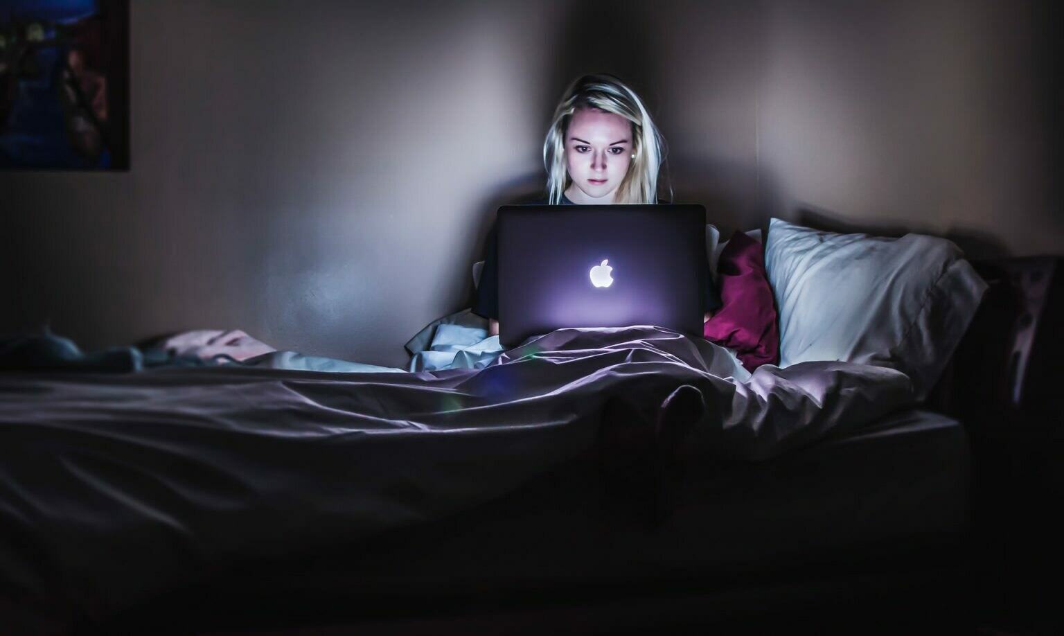a person sitting on a bed with a laptop on the lap