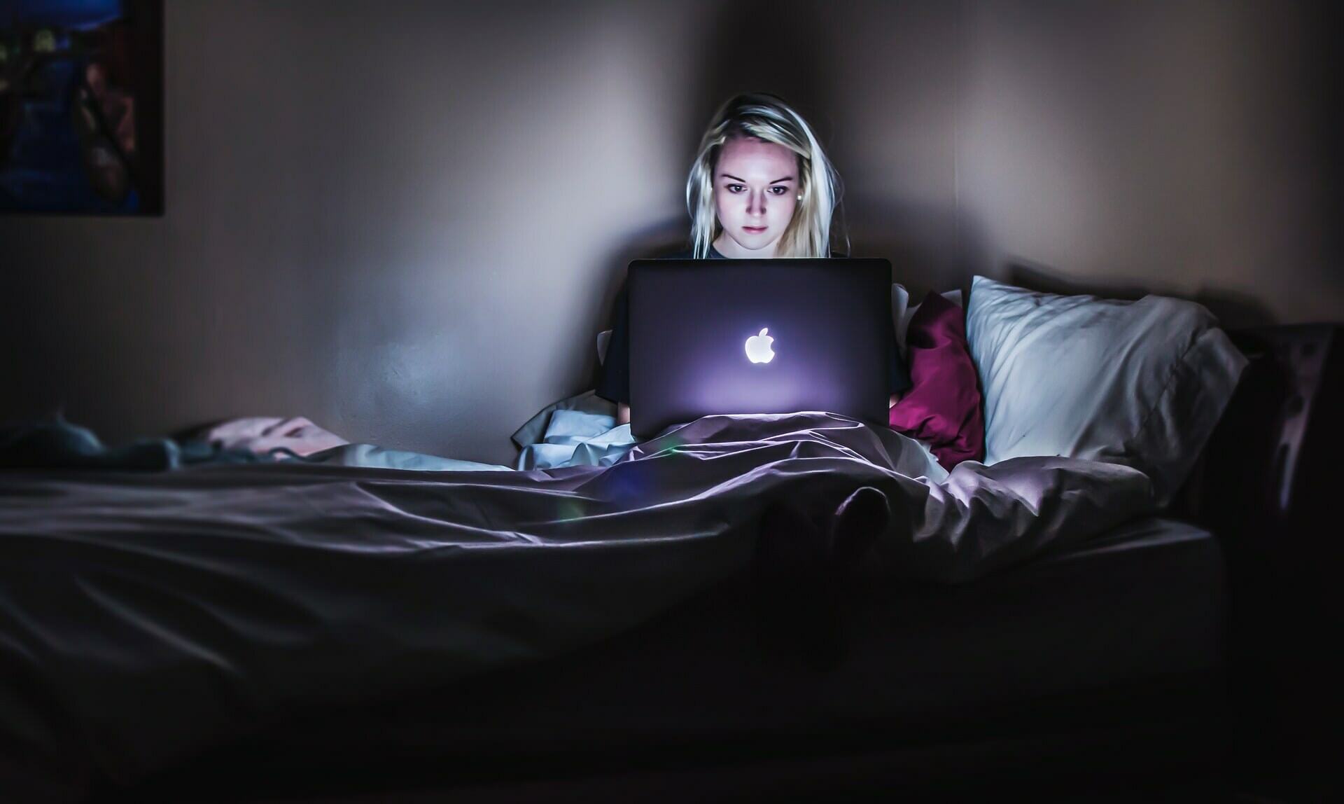 a person sitting on a bed with a laptop on the lap