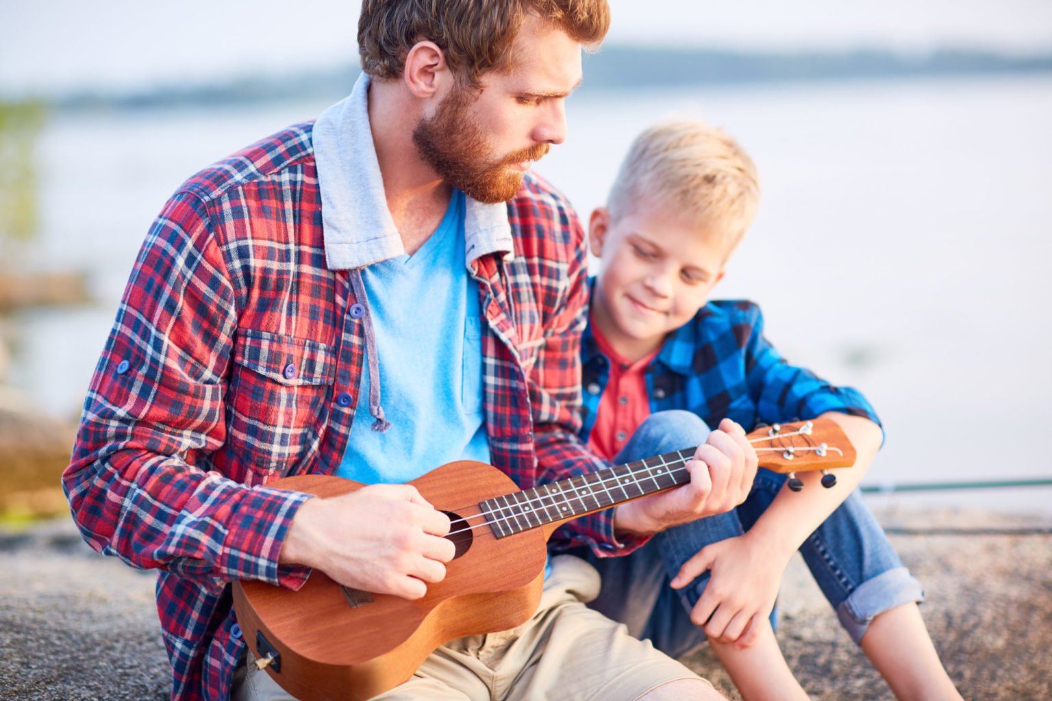 a person playing a guitar with a young boy sitting on a bench