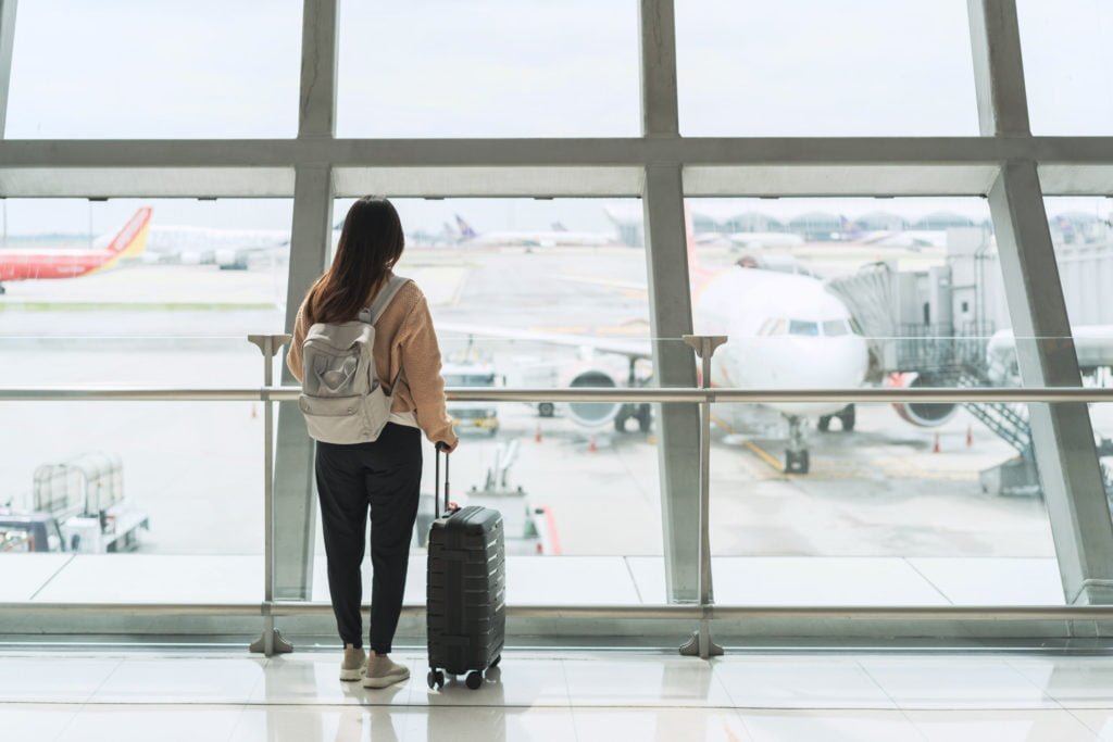 Young woman traveler looking at the airplane at the airport, Travel concept