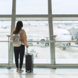 Young woman traveler looking at the airplane at the airport, Travel concept