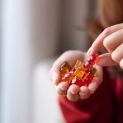 Closeup image of a woman holding and picking a jelly gummy bear