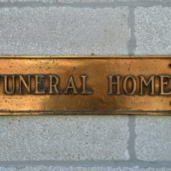 A brass Funeral Home sign on a wall. Morticians, funeral directors