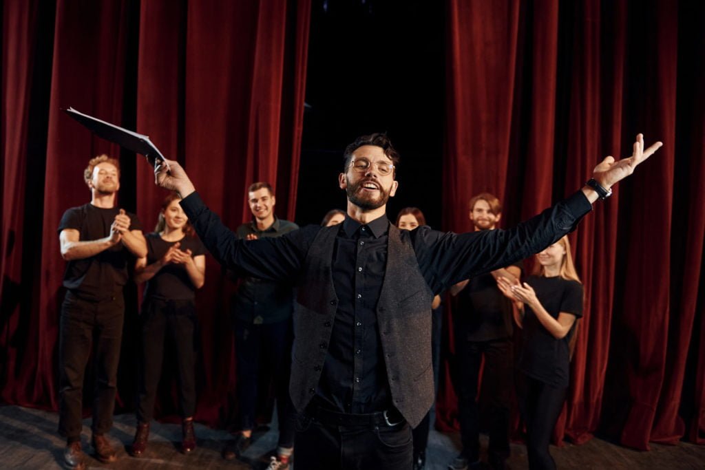 Group of actors in dark colored clothes on rehearsal in the theater