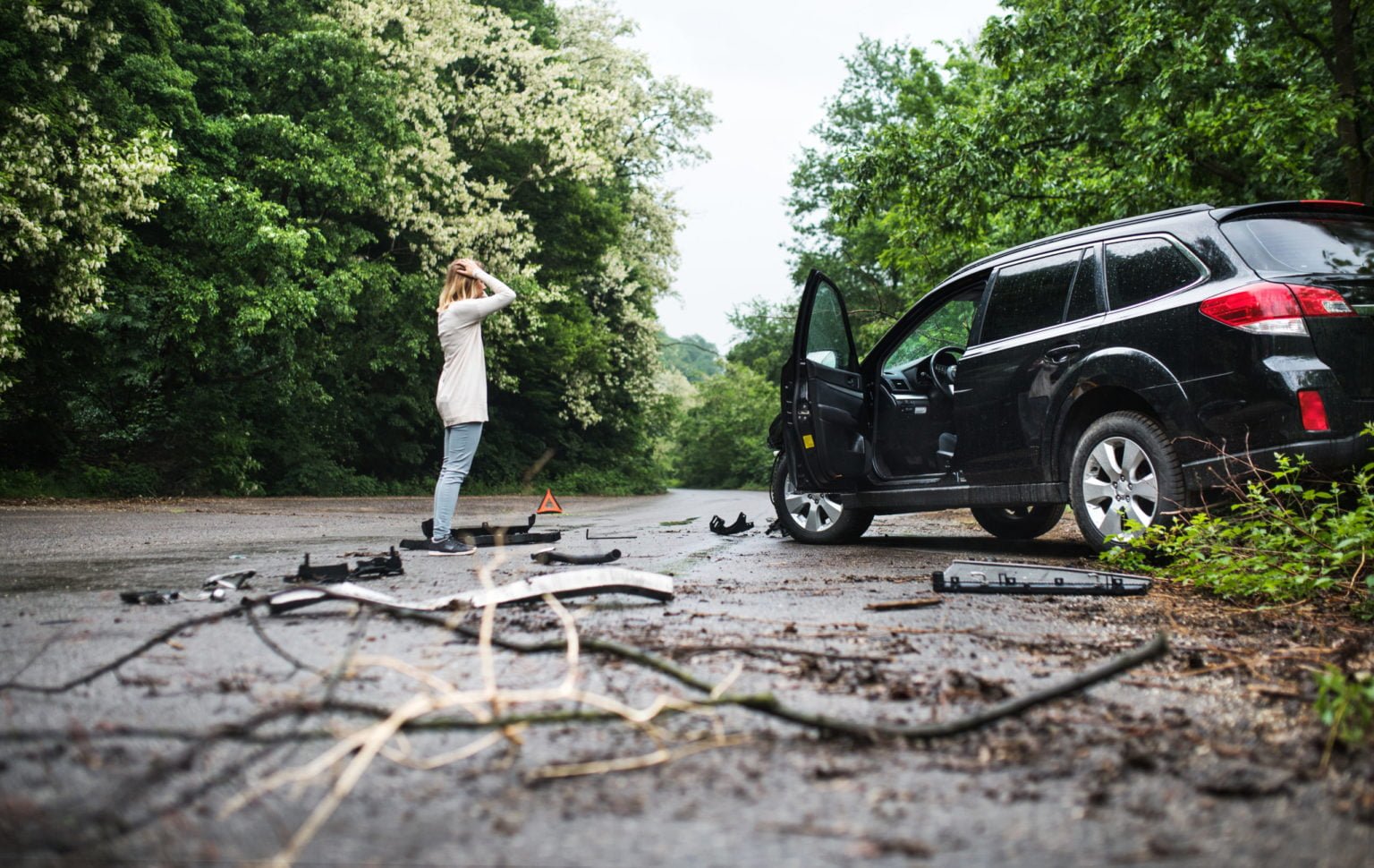 Young woman standing by the damaged car after a car accident.