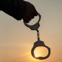 Business Man holding handcuffs after releasing over sunset background
