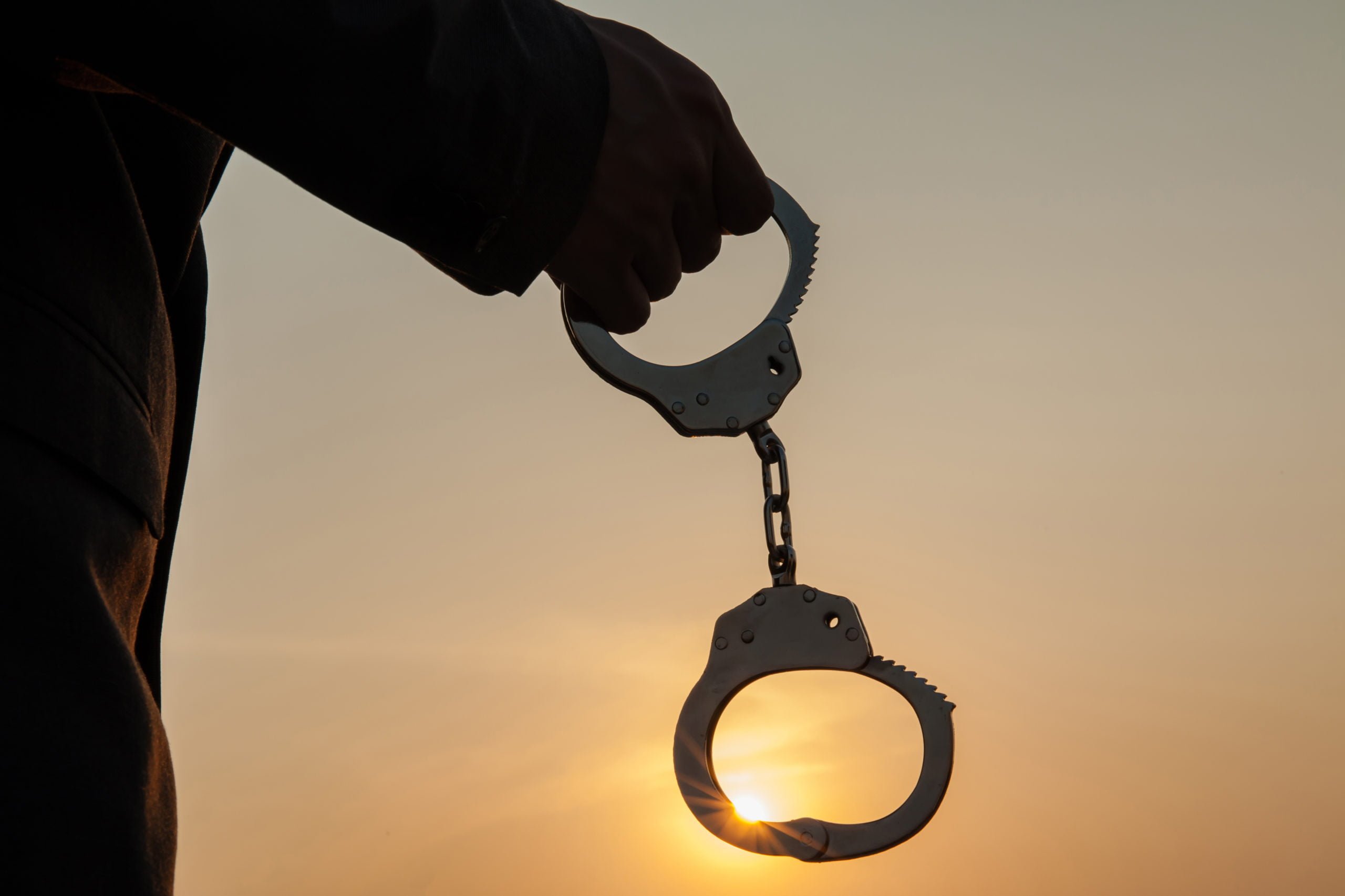 Business Man holding handcuffs after releasing over sunset background