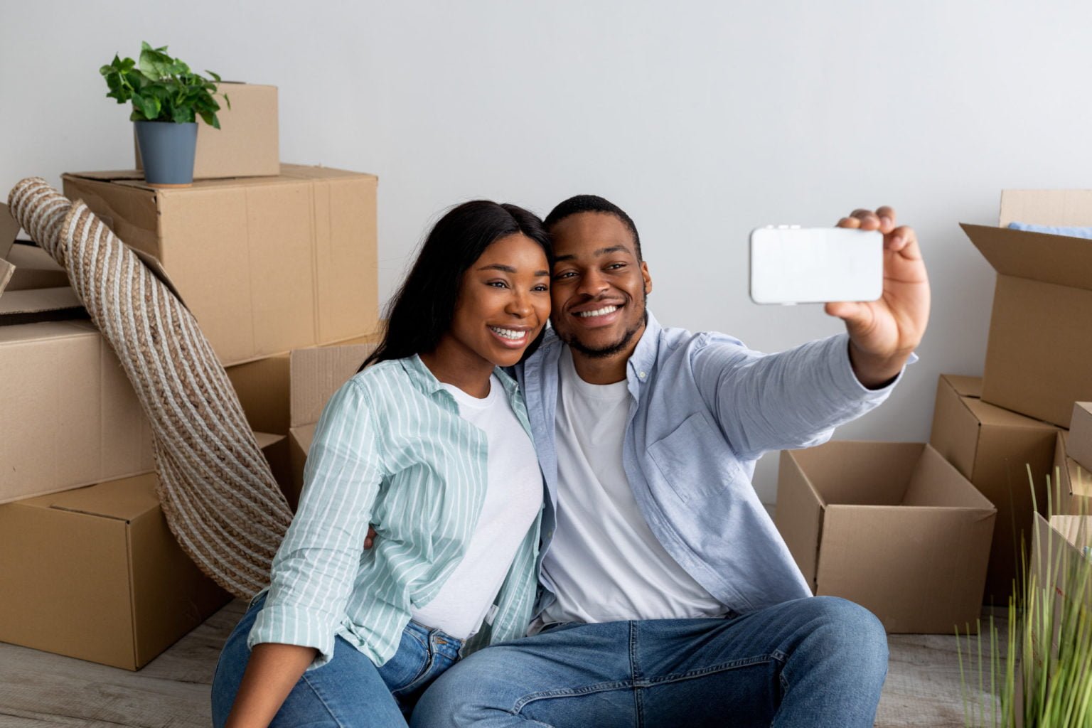 Relocation and ownership concept. Happy young black couple making selfie after moving to own house