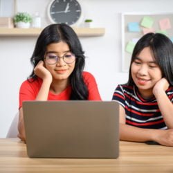 two young women working on a laptop