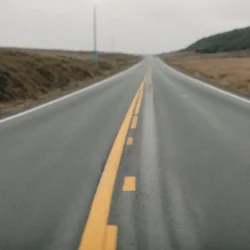 a smooth, freshly paved road stretching into the distance, flanked by construction markers.