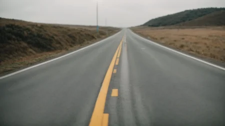 a smooth, freshly paved road stretching into the distance, flanked by construction markers.